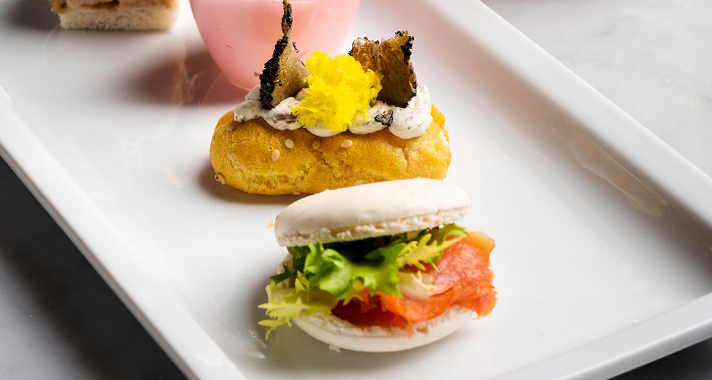 Catering: bignè farcito e macaron salmone su vassoio. Finger food gourmet per eventi e ricevimenti.