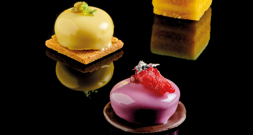 Dolci gourmet su sfondo nero. Pasticceria artigianale, dessert colorati e raffinati. Assortimento di mini torte.