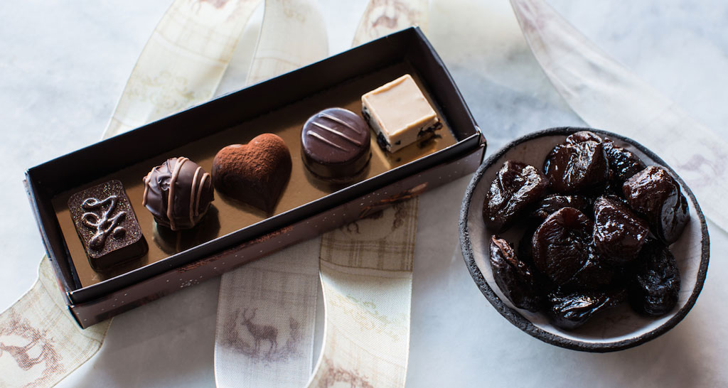 Cioccolatini assortiti e prugne della California in ciotola. Dolci prelibatezze e frutta secca.