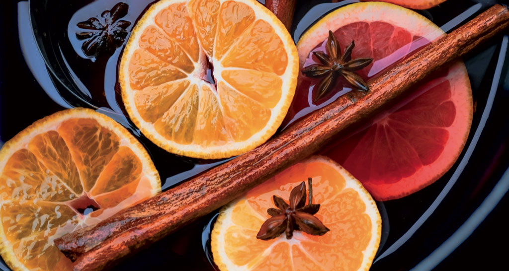 Agrumi, anice stellato e cannella in infusione. Preparazione di vin brulé o punch caldo.