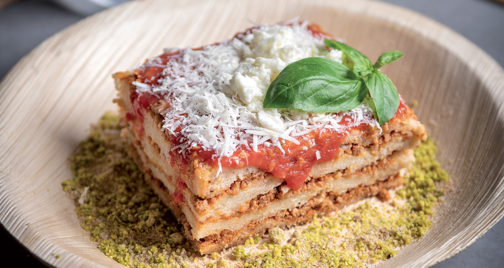 Lasagna di pizza al ragù, pranzo delizioso. Ricotta, basilico e parmigiano grattugiato.