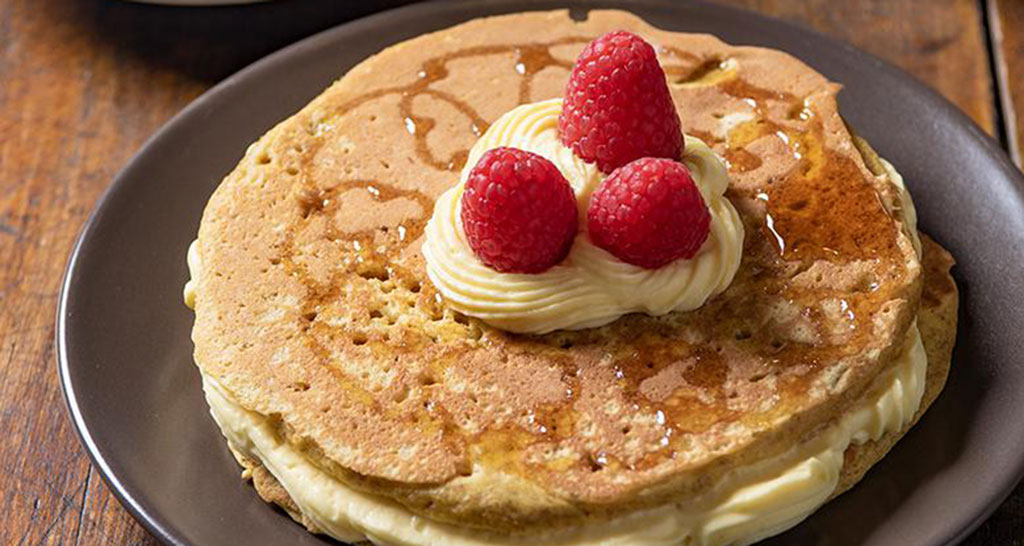 Pancake con crema chantilly e lamponi. Dolce goloso.