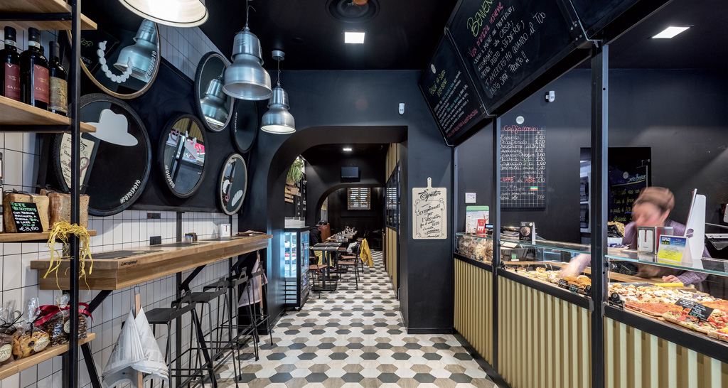 Interni di Spoto Bakery, locale con bancone, tavoli, sedie e decorazioni. Design moderno e accogliente.