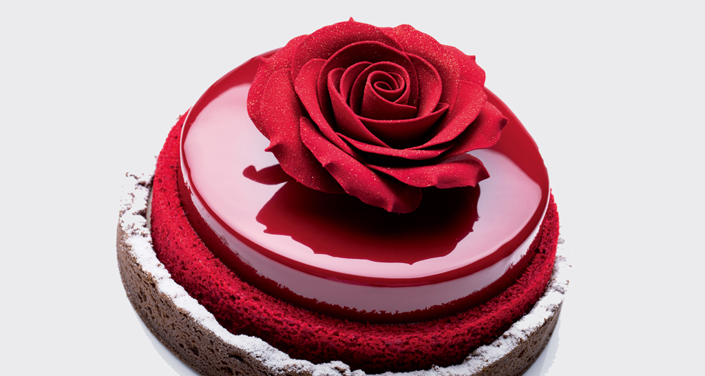 Torta elegante con glassa rossa lucida e rosa decorativa. Pasticceria raffinata.