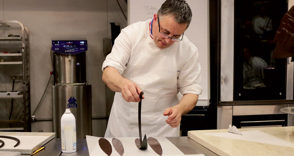 Chef pasticcere al lavoro con cioccolato. Preparazione artigianale di dolci al cioccolato.