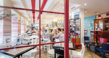 Interno di ristorante arredato con tavoli, sedie e decorazioni rosse e bianche. Design accogliente.