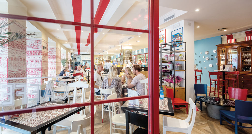 Interno di ristorante arredato con tavoli, sedie e decorazioni rosse e bianche. Design accogliente.