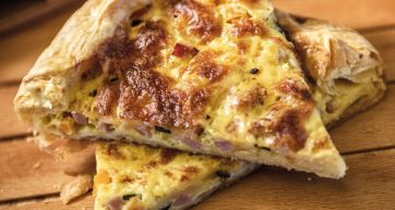 Fetta di quiche lorraine con prosciutto e formaggio. Torta salata rustica.