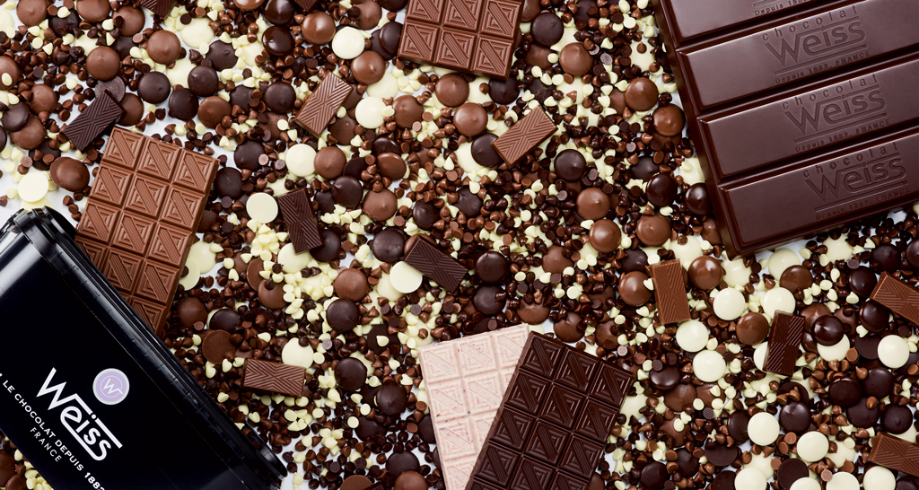 Assortimento di cioccolato Weiss: tavolette, gocce e dischi. Cioccolato fondente, al latte e bianco. Delizie al cioccolato.