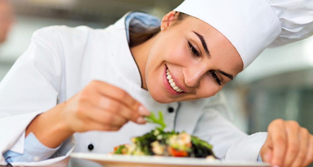 Chef donna guarnisce piatto gourmet. Cucina professionale, alta cucina italiana.