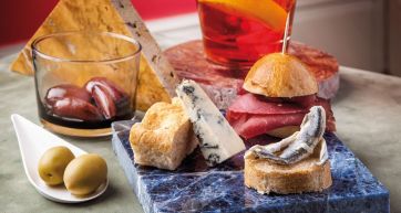 Aperitivo italiano con cocktail, olive, formaggio, salumi e pane. Food photography.
