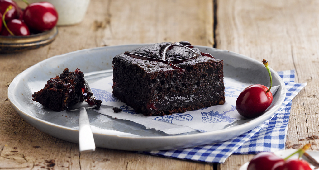Brownie al cioccolato con ciliegie fresche su piatto. Dessert goloso, ideale per colazione o merenda.
