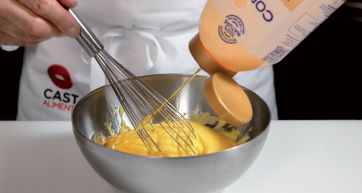 Preparazione maionese: olio versato in ciotola con uova e frusta. Ricetta facile e veloce.