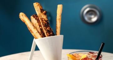 Grissini artigianali in bicchiere con cocktail. Aperitivo italiano, snack salato.