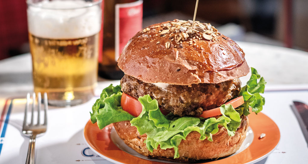 Hamburger gourmet con birra. Panino con carne, pomodoro e insalata. Idea per pranzo o cena.