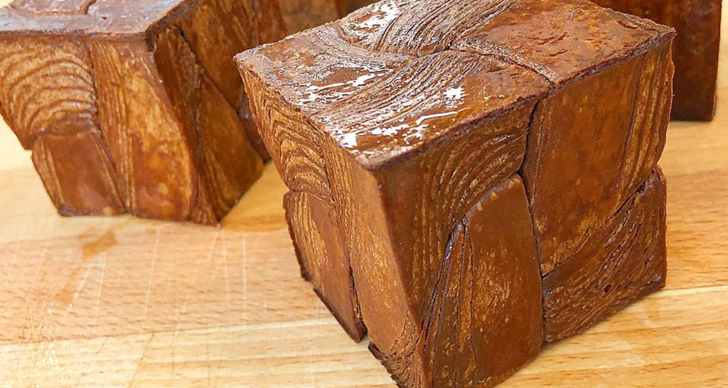 Dolce cubo di pasticceria. Strati di pasta sfoglia marrone lucido. Delizia artigianale.