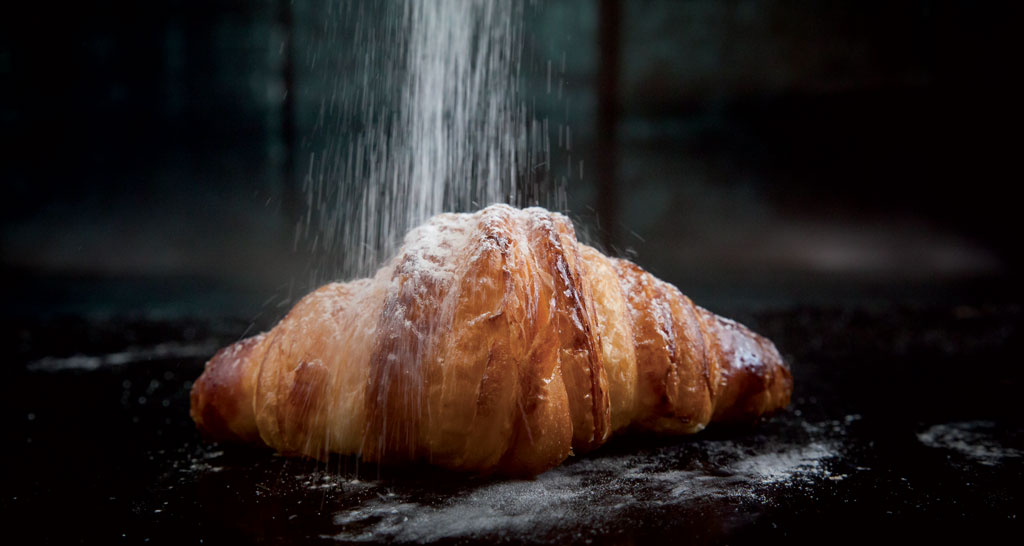 Croissant dorato con zucchero a velo. Pasticceria francese, colazione dolce.