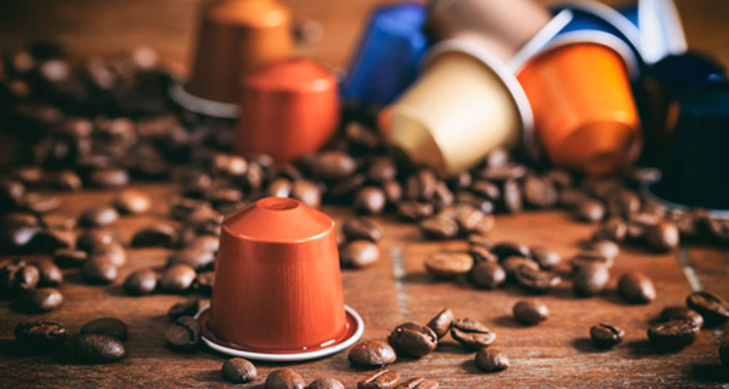 Capsule caffè espresso colorate e chicchi di caffè su legno. Aroma intenso.