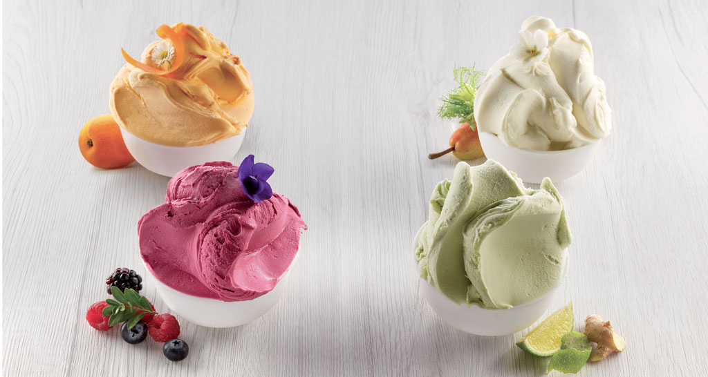 Quattro coppette di gelato artigianale ai gusti di frutta fresca. Dessert estivo.