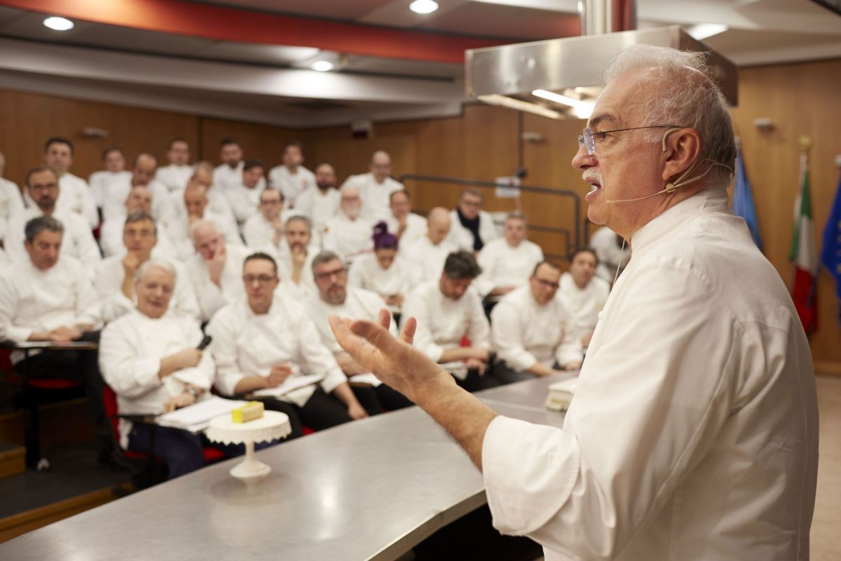Chef italiano tiene lezione di cucina. Gruppo di chef ascoltano in aula. Cucina italiana, formazione professionale.