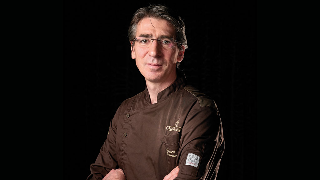 Ritratto di chef pasticcere in giacca marrone. Cucina d'alta qualità, esperto di dolci e cioccolato.