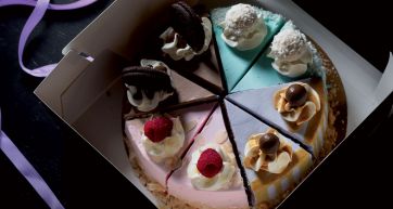 Assortimento di torte miste in confezione. Dolci con panna, cioccolato, cocco e lamponi. Idea regalo golosa.