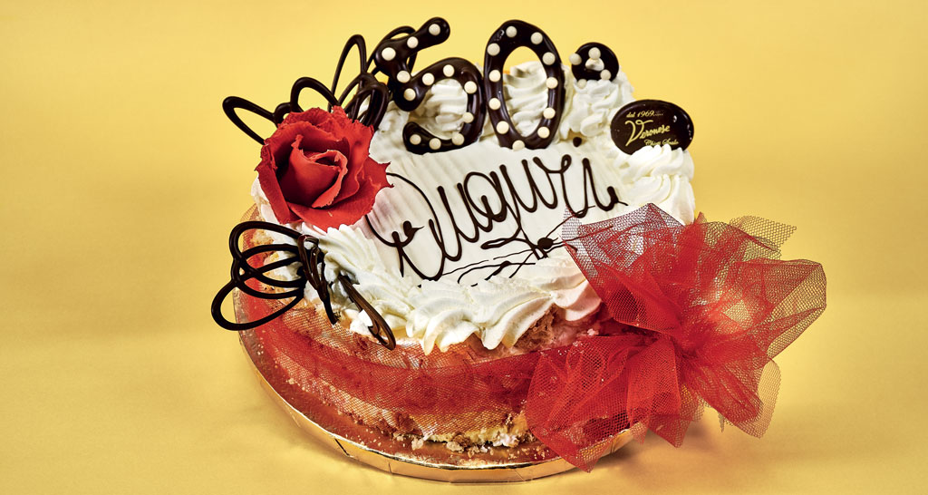 Torta di compleanno decorata per 50 anni. Auguri con rosa rossa e fiocco.
