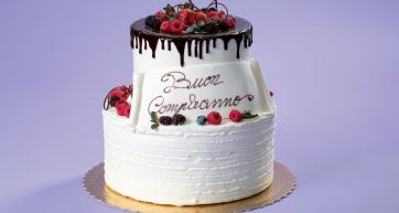 Torta di compleanno a due piani con cioccolato e frutti di bosco. Scritta Buon Compleanno.