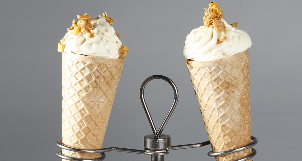 Gelato artigianale in cono waffle con granella. Dessert fresco e goloso.