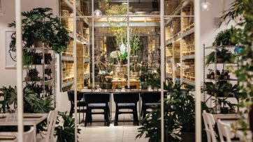 Interno ristorante elegante. Tavolo apparecchiato, piante decorative, scaffali con prodotti. Design d'interni.