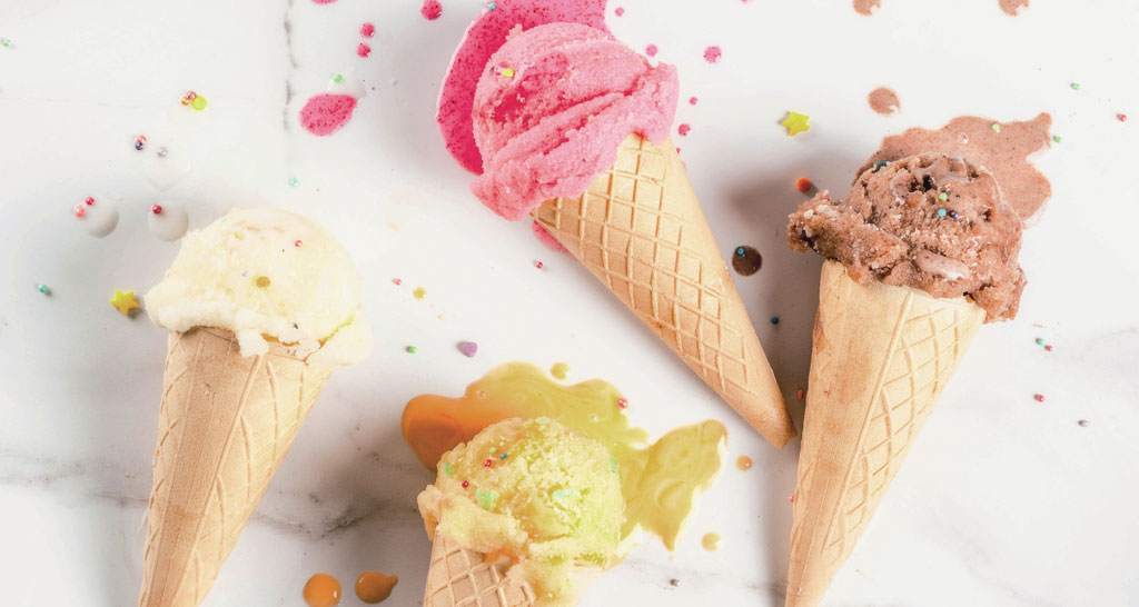 Gelati colorati in coni waffle. Dessert estivo con palline di gelato che si sciolgono.