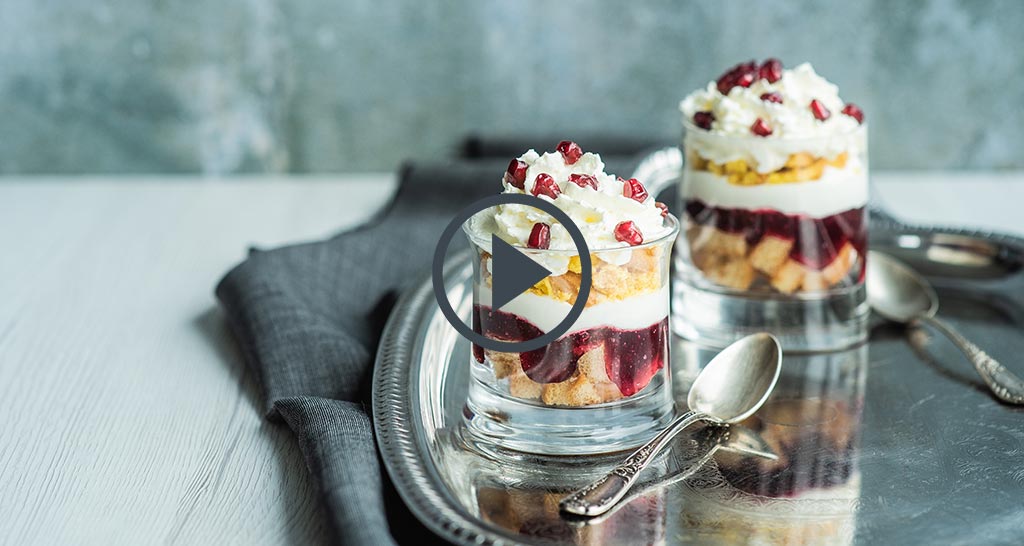 Dolce in bicchiere con melograno e panna. Dessert a strati con frutta fresca. Idea golosa per fine pasto.