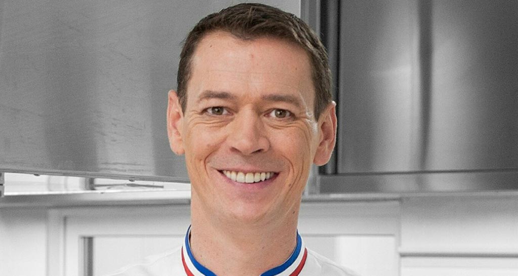 Ritratto di Jérôme Ferrer, chef francese sorridente. Cucina professionale, alta gastronomia.