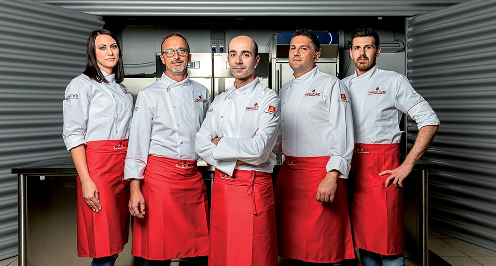 Team di chef esperti. Divise bianche e grembiuli rossi. Cucina professionale.