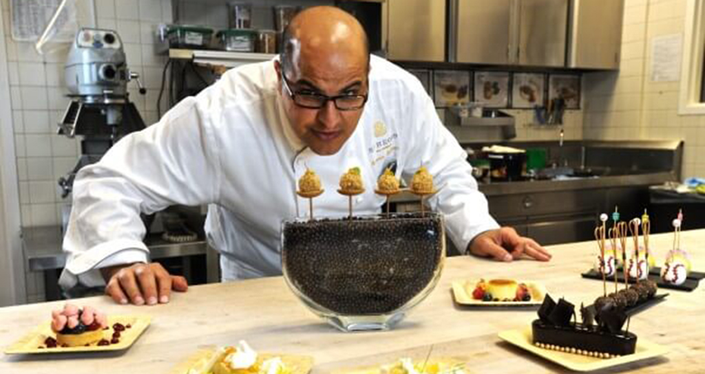 Chef pasticcere con dolci gourmet. Dessert al cioccolato e frutta fresca. Cucina professionale.