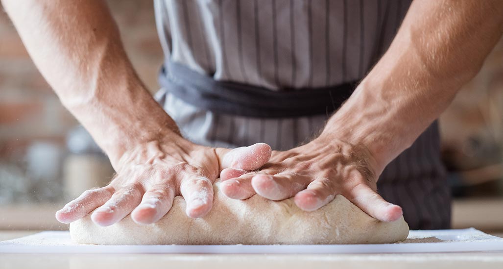 Impasto fatto in casa. Mani che lavorano la pasta lievitata, farina. Ricetta pane, pizza.