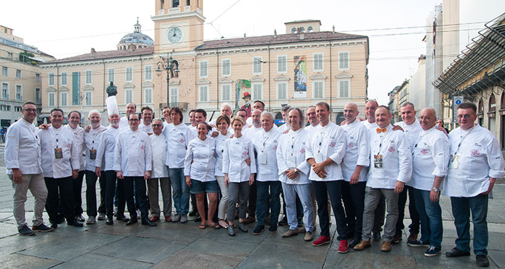 Gruppo di maestri lievitisti in posa. Evento gastronomico, chef in divisa bianca. Parma, Italia.