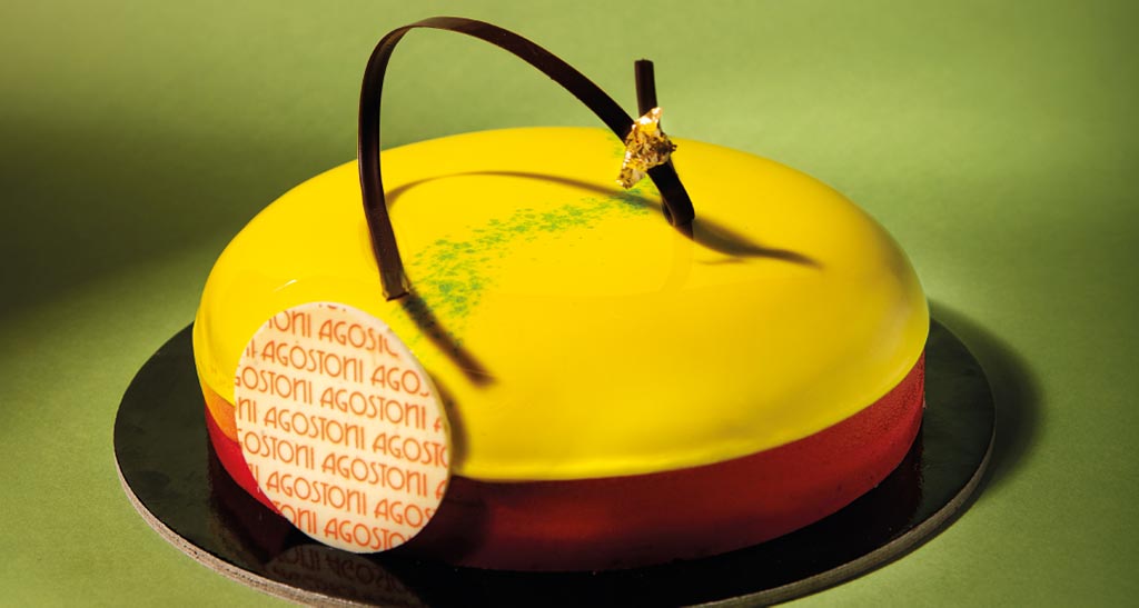 Torta moderna Agostoni con glassa gialla, decorazioni di cioccolato e foglia d'oro. Dolce di pasticceria.