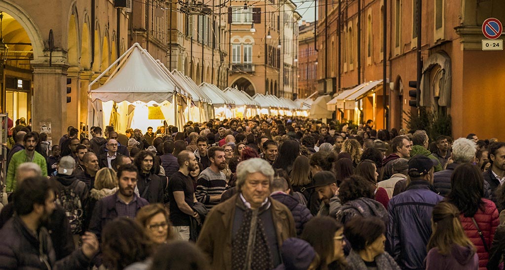 Folla al festival del cioccolato. Bancarelle illuminate, architettura storica. Evento gastronomico affollato.