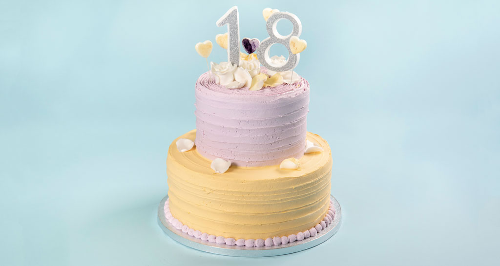 Torta di compleanno a due piani per 18 anni, decorata con cuori e petali.
