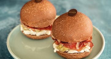 Due panini gourmet con prosciutto e formaggio su piatto. Panini artigianali, cibo italiano.