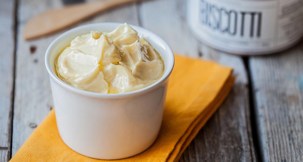 Margarina cremosa in ciotola bianca su tovagliolo arancione. Alternativa al burro, ideale per cucinare e spalmare.