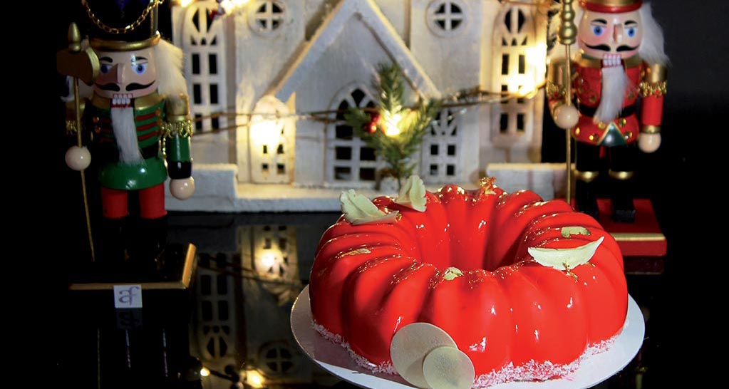 Torta natalizia rossa con decorazioni, schiaccianoci e casetta illuminata. Dolci di Natale.