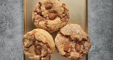Dolci italiani: biscotti di mandorla artigianali su vassoio dorato. Pasticceria secca, dessert goloso.