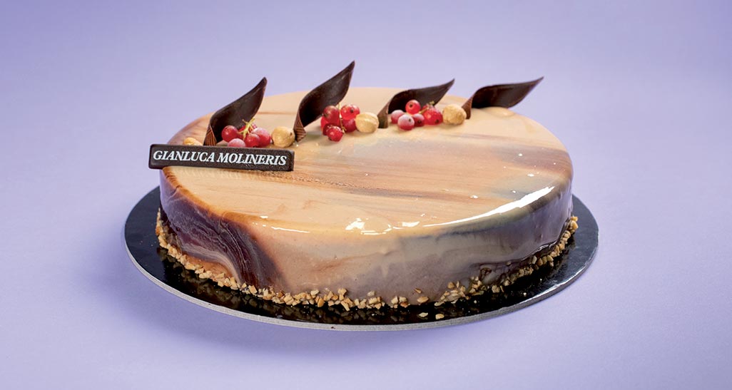 Torta nocciolosa di Gianluca Molineris. Dessert elegante con glassa lucida, ribes e cioccolato.
