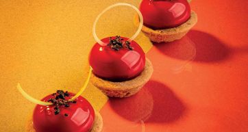 Dolci rossi su tartellette. Dessert eleganti con glassa lucida e decorazioni. Pasticceria creativa.