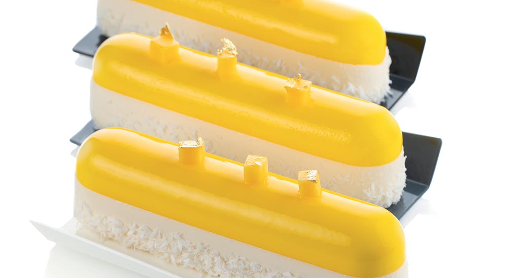 Tre éclair gialli e bianchi. Dessert elegante con decorazioni dorate. Pasticceria raffinata.