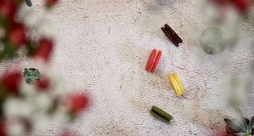 Macarons colorati su sfondo neutro con decorazioni floreali. Dolci francesi.