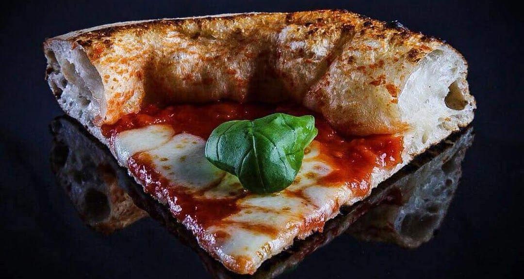 Fetta di pizza margherita con basilico. Pizza napoletana con mozzarella e pomodoro.