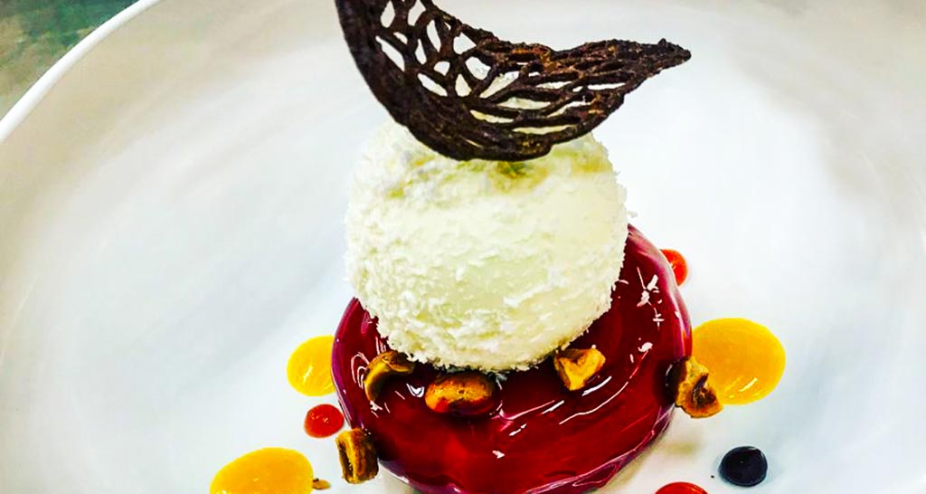 Dolce gourmet: sfera bianca, gelatina rossa, decorazione di cioccolato. Dessert elegante e creativo.